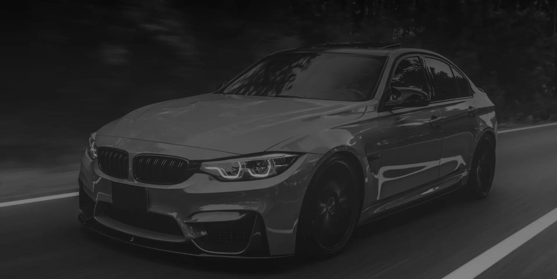 A dark sedan driving fast along a road